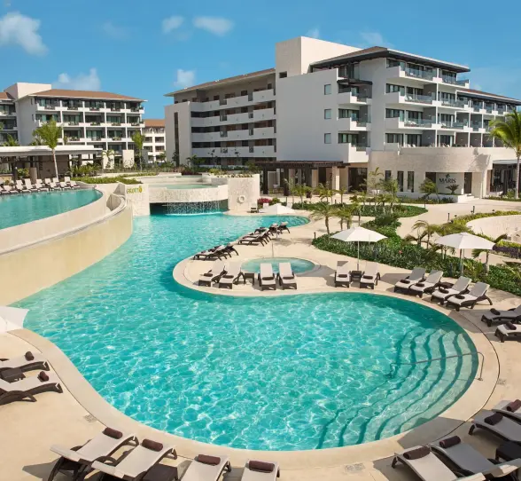 Multi-level pool at Dreams Playa Mujeres with waterfalls, sun loungers, and tropical garden views.