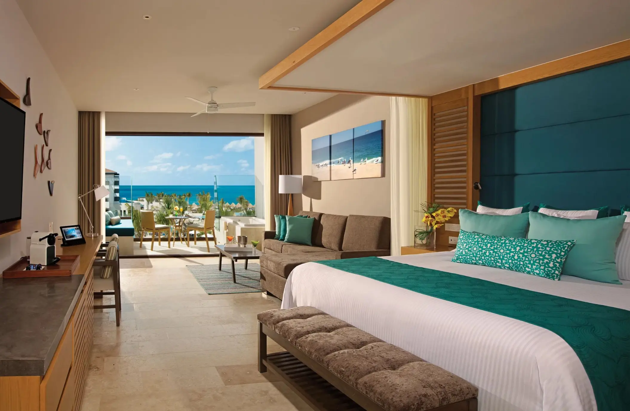 Junior suite with ocean view, king bed, cozy seating area, and furnished balcony at Dreams Resort.