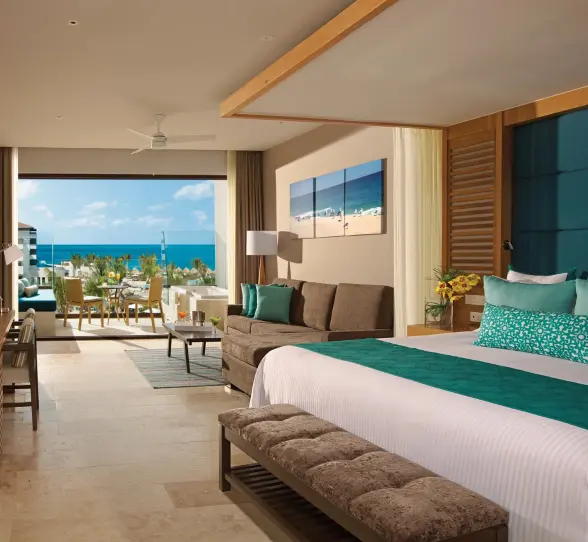 Junior suite with ocean view, king bed, cozy seating area, and furnished balcony at Dreams Resort.