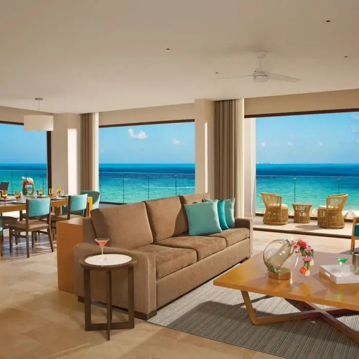 Family presidential suite living and dining area with sweeping ocean views and modern beach decor.