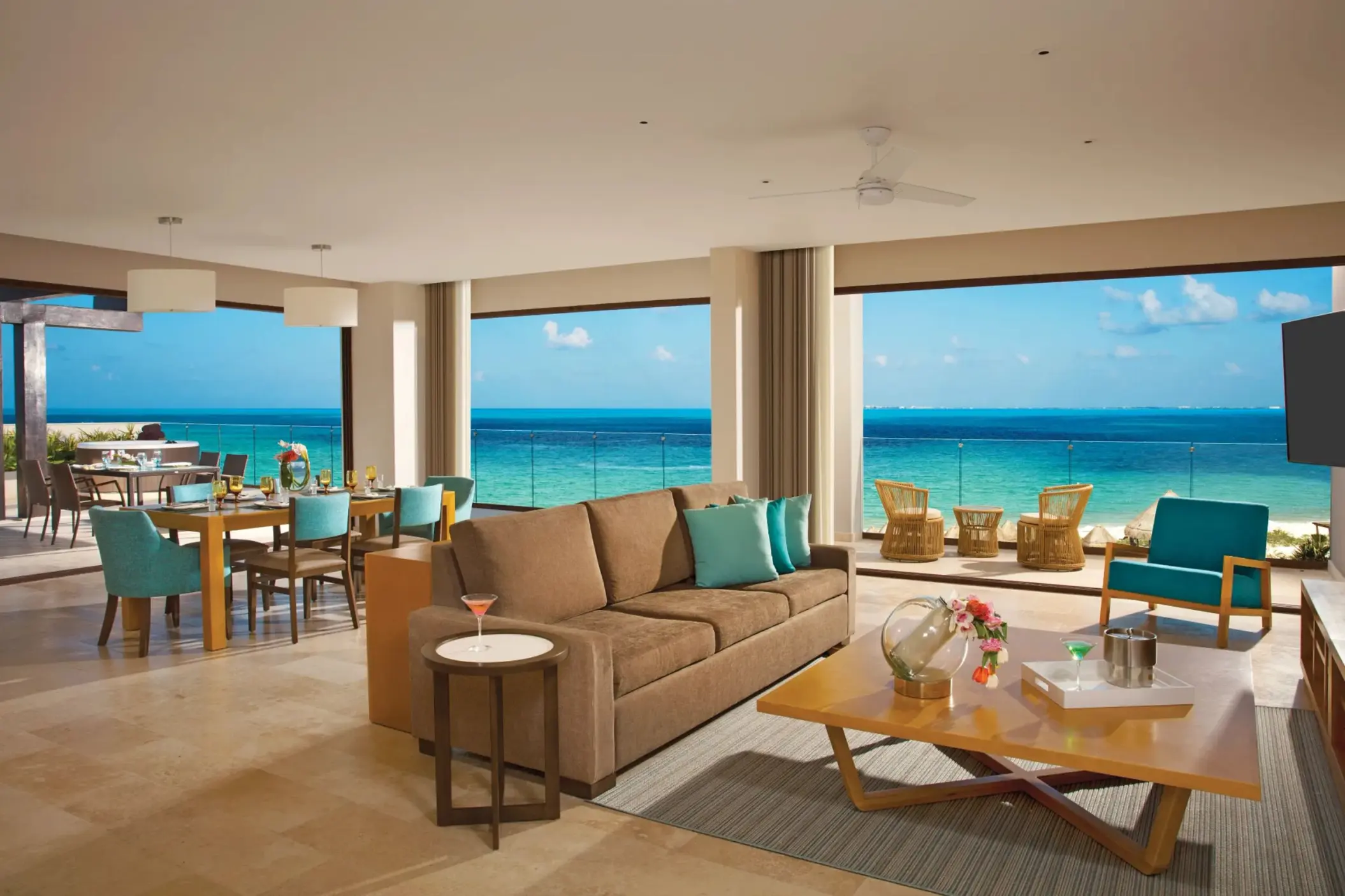 Family presidential suite living and dining area with sweeping ocean views and modern beach decor.