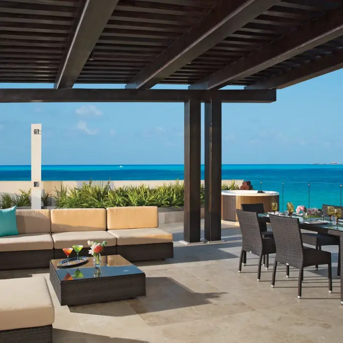 Expansive terrace with ocean views, lounge seating, and dining area in family presidential suite.