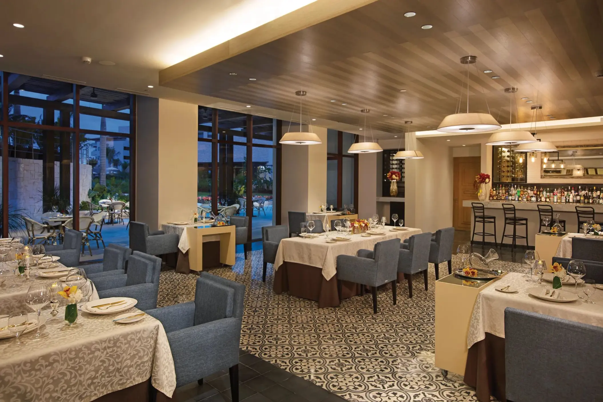 L’Etoile restaurant showcases elegant fine dining with blue chairs, patterned floors, and warm ambient lighting.