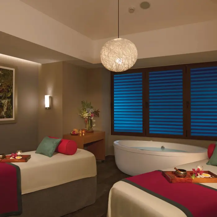 Peaceful couples’ spa cabin with massage tables, a soaking tub, and calming, low-lit ambiance.