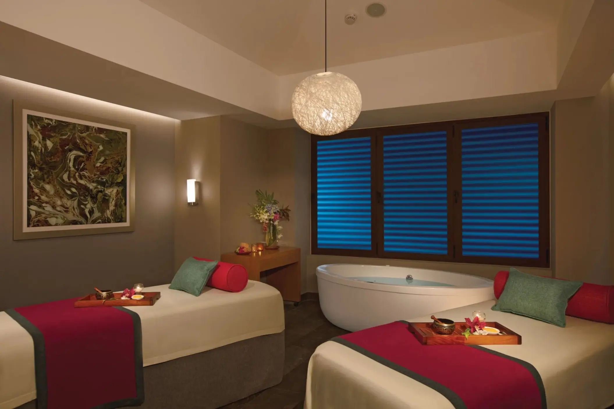 Peaceful couples’ spa cabin with massage tables, a soaking tub, and calming, low-lit ambiance.