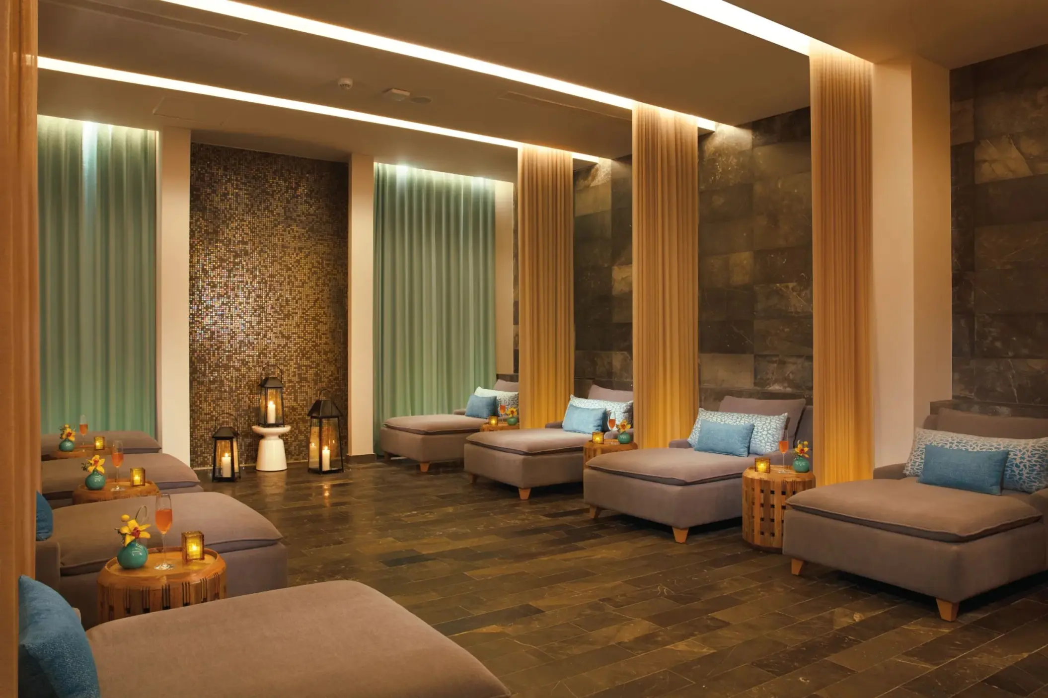 Tranquil spa relaxation lounge with daybeds, soft lighting, and soothing decor in natural tones.