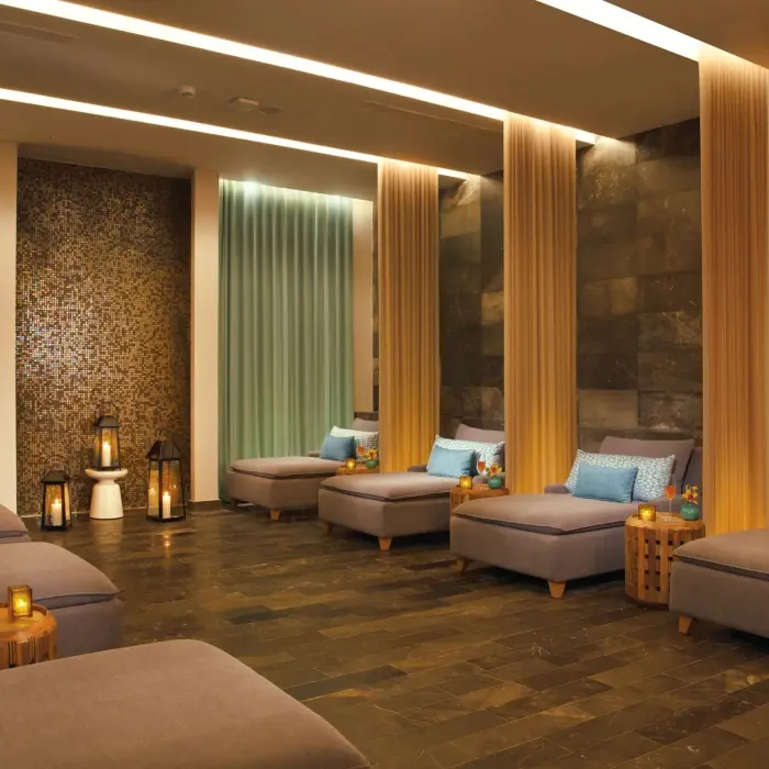 Tranquil spa relaxation lounge with daybeds, soft lighting, and soothing decor in natural tones.
