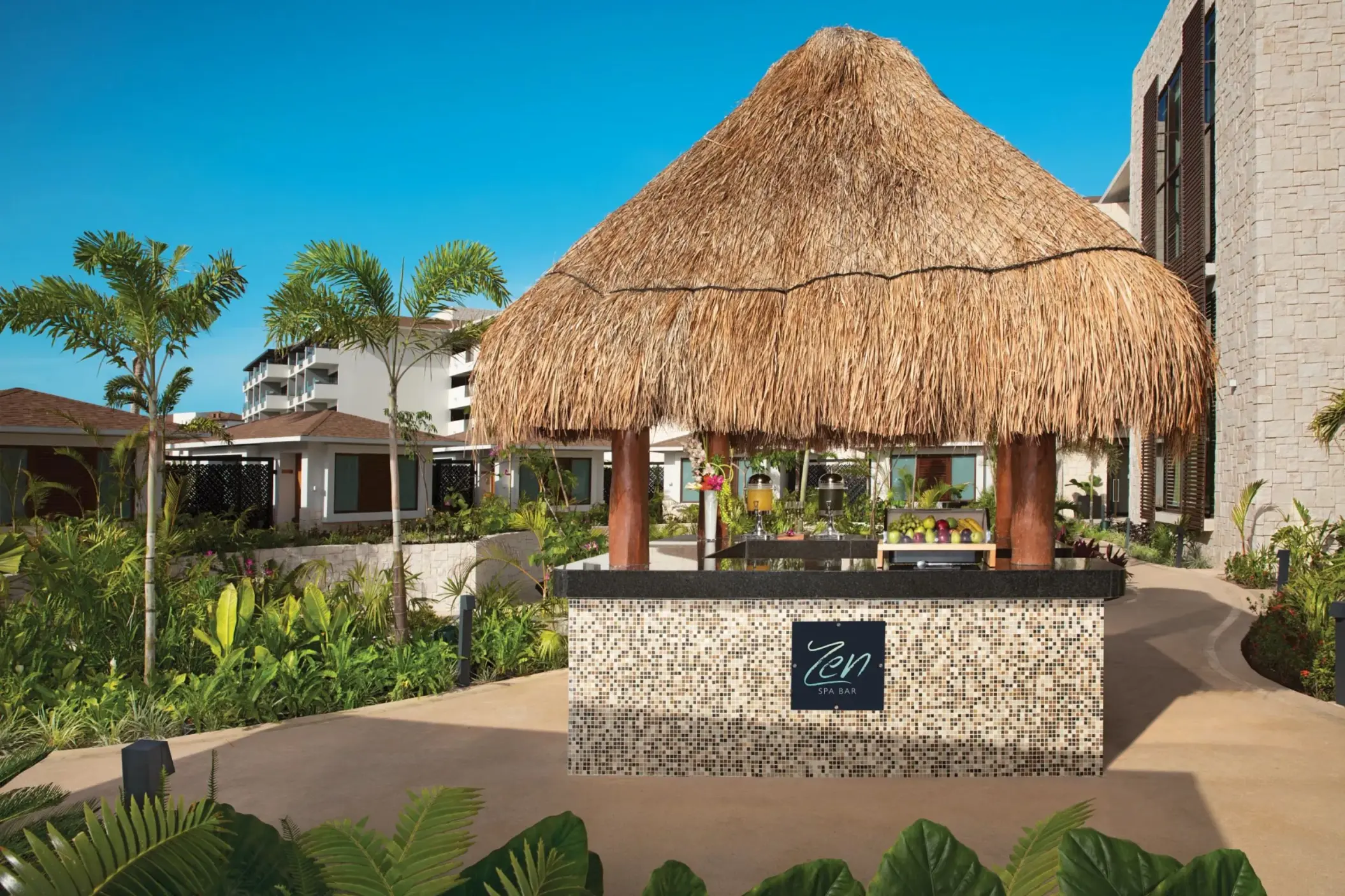 Zen Spa Bar with thatched roof and a counter offering fresh fruit and juices in a lush garden setting.