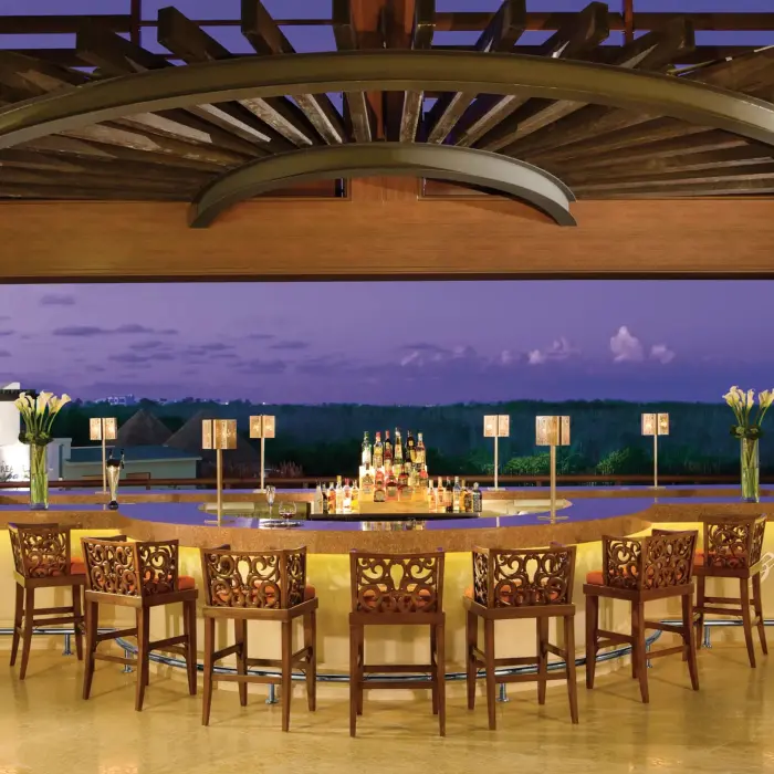 Sophisticated Rendezvous Bar at Dreams Riviera Cancun with circular seating and sunset views from lobby level.