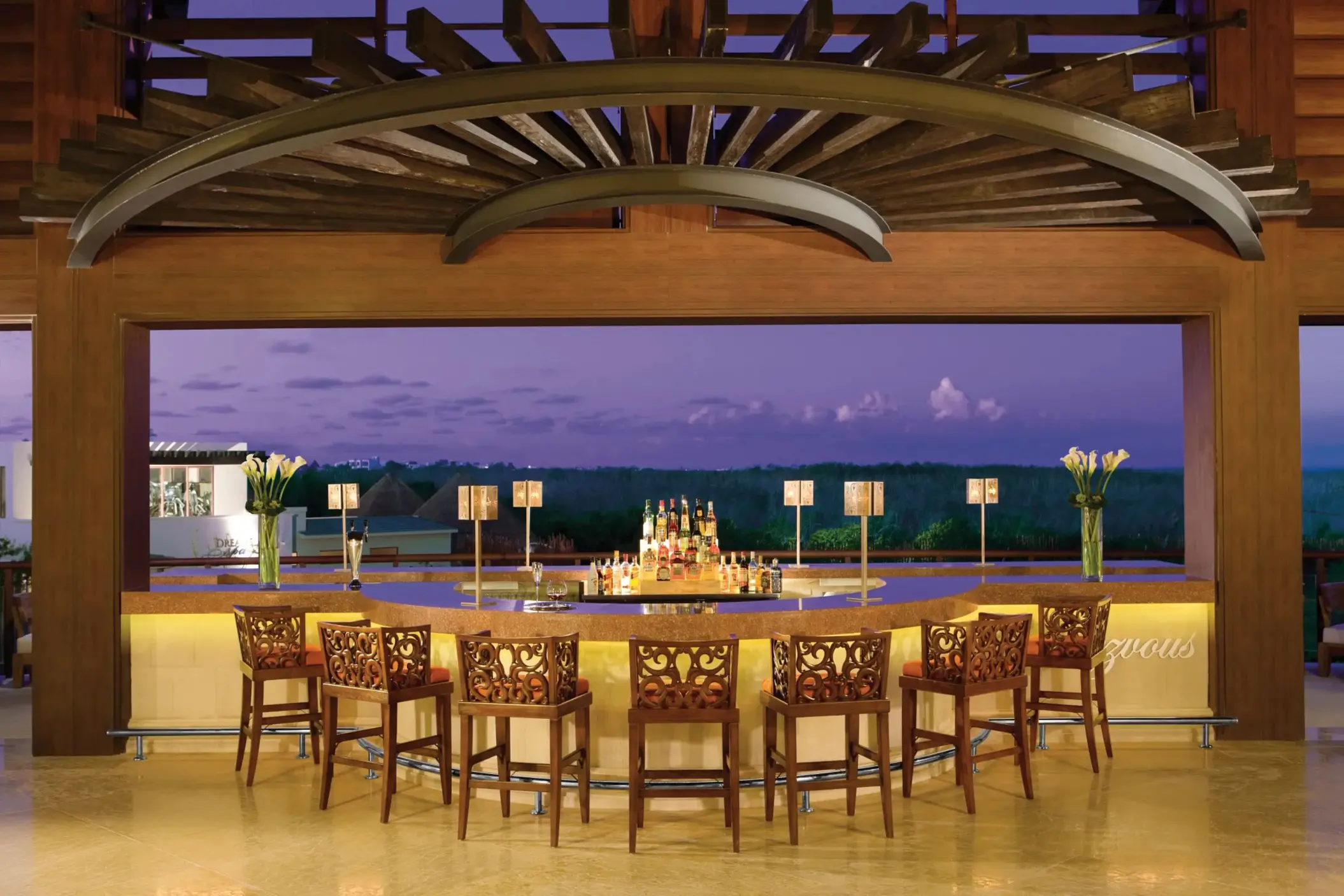 Sophisticated Rendezvous Bar at Dreams Riviera Cancun with circular seating and sunset views from lobby level.