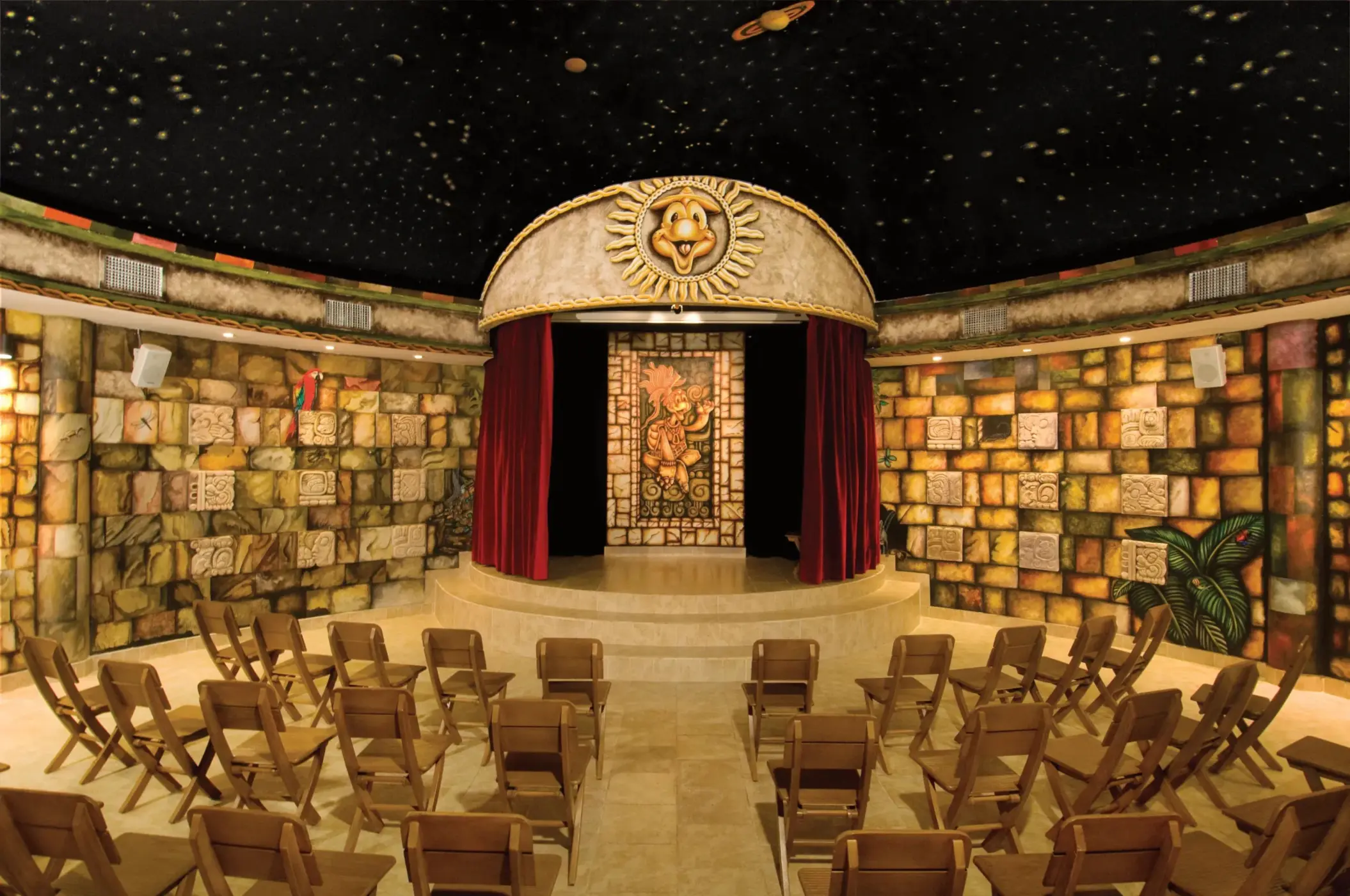Explorer’s Club indoor kids’ theater with stage, red curtains, and Mayan-inspired décor.