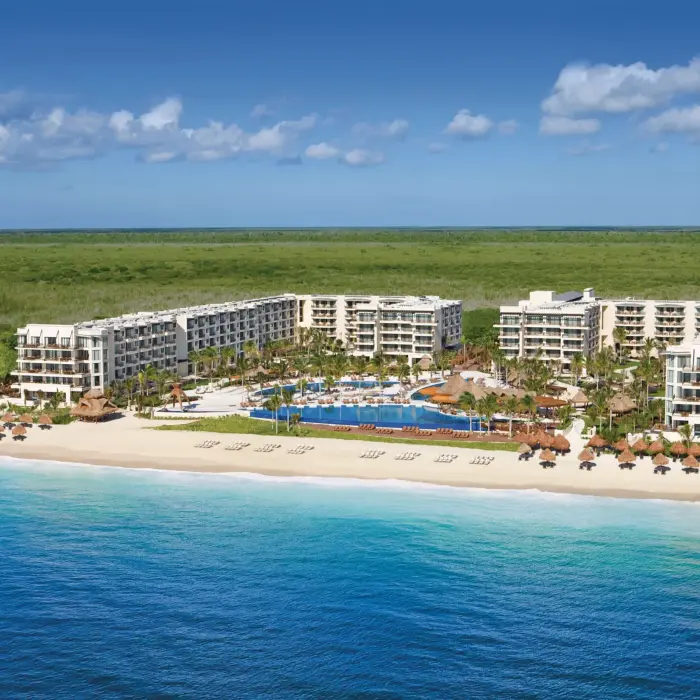 Aerial image of Dreams resort surrounded by forest, overlooking a white-sand beach.