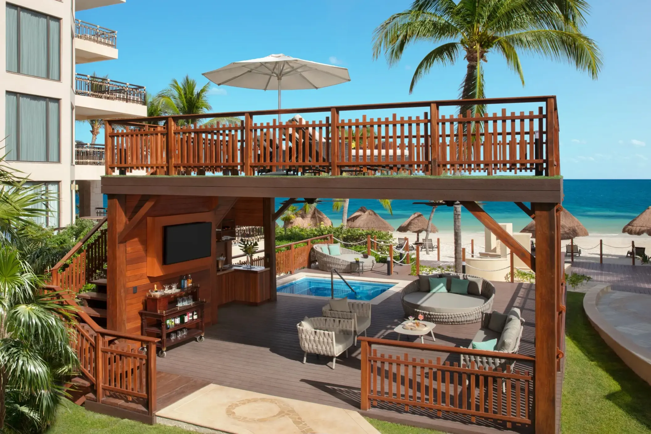 Outdoor beach cabana with lounge seating, sun deck and ocean backdrop.