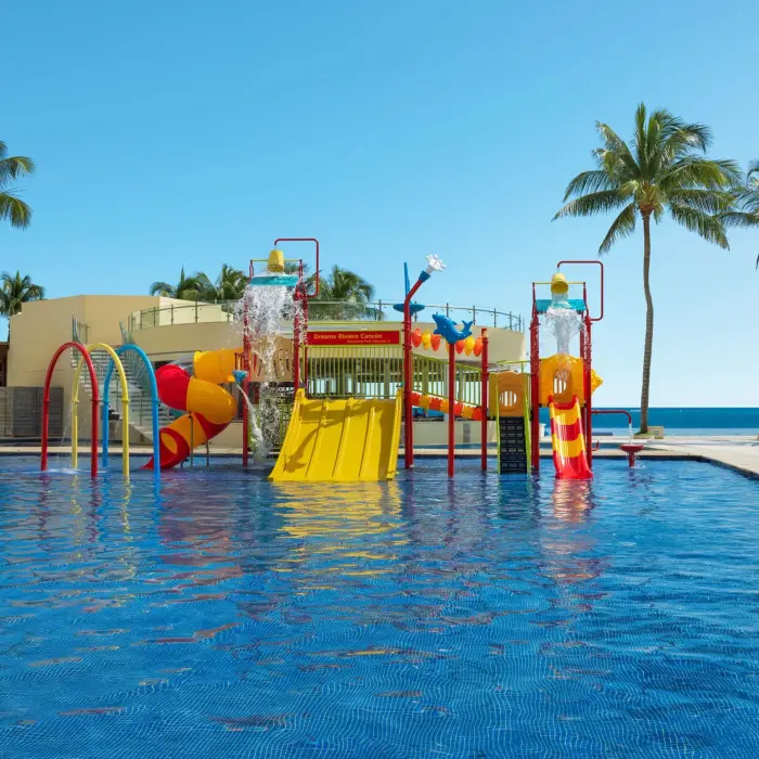 Colorful beachfront waterpark with slides, splash buckets, and kids’ play features at Dreams Riviera Cancun Resort.