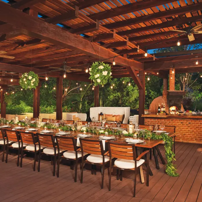 Outdoor Chef’s Table Gala setup with string lights, greenery, and a wood-fired oven.