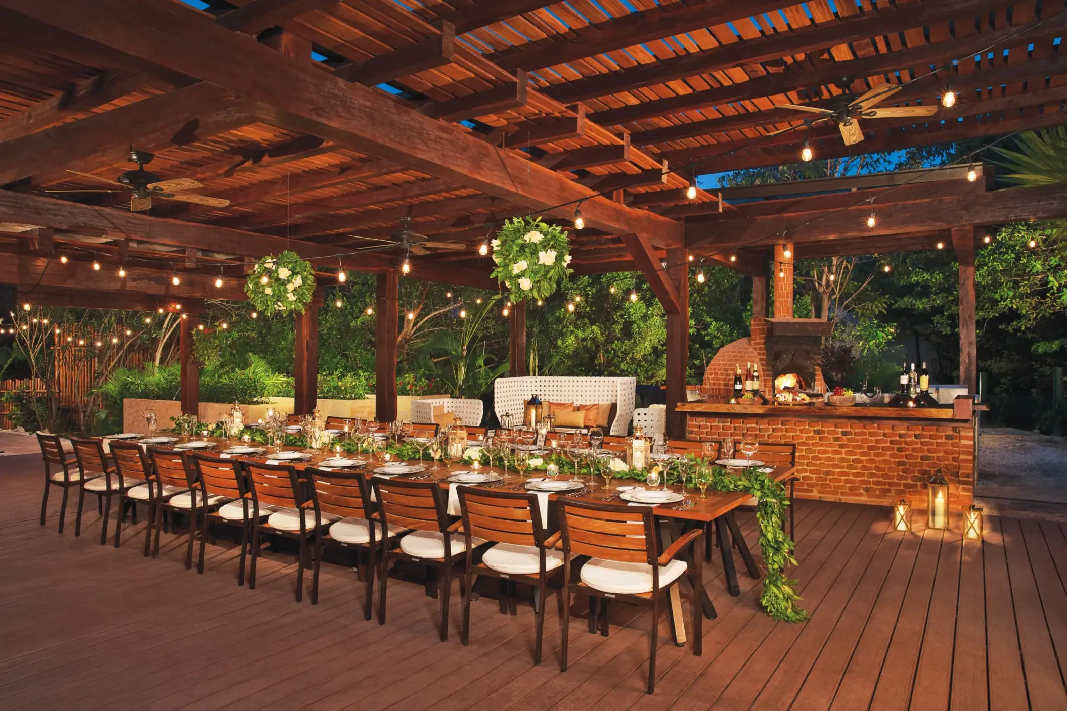 Outdoor Chef’s Table Gala setup with string lights, greenery, and a wood-fired oven.