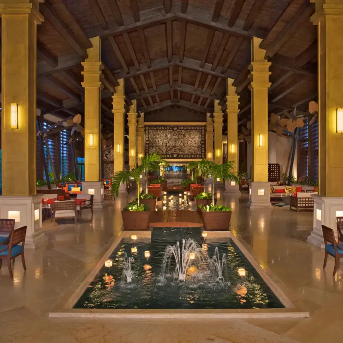 Elegant resort lobby with high ceilings, central fountain and tropical decor.