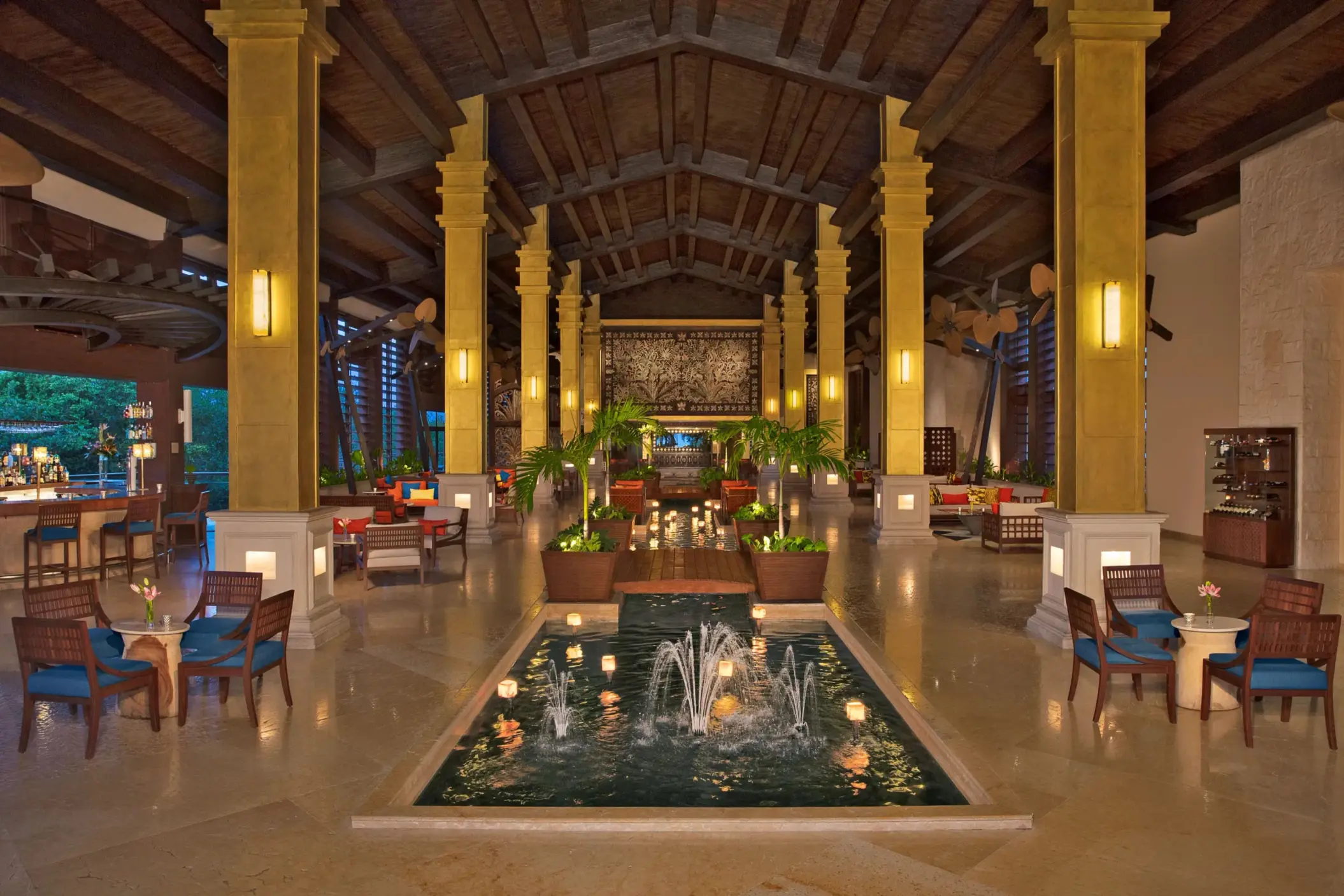 Elegant resort lobby with high ceilings, central fountain and tropical decor.