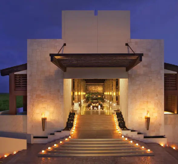 Resort lobby illuminated at night with candlelit steps and warm golden tones.