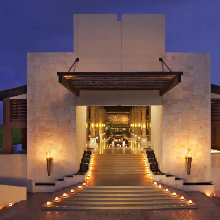 Resort lobby illuminated at night with candlelit steps and warm golden tones.
