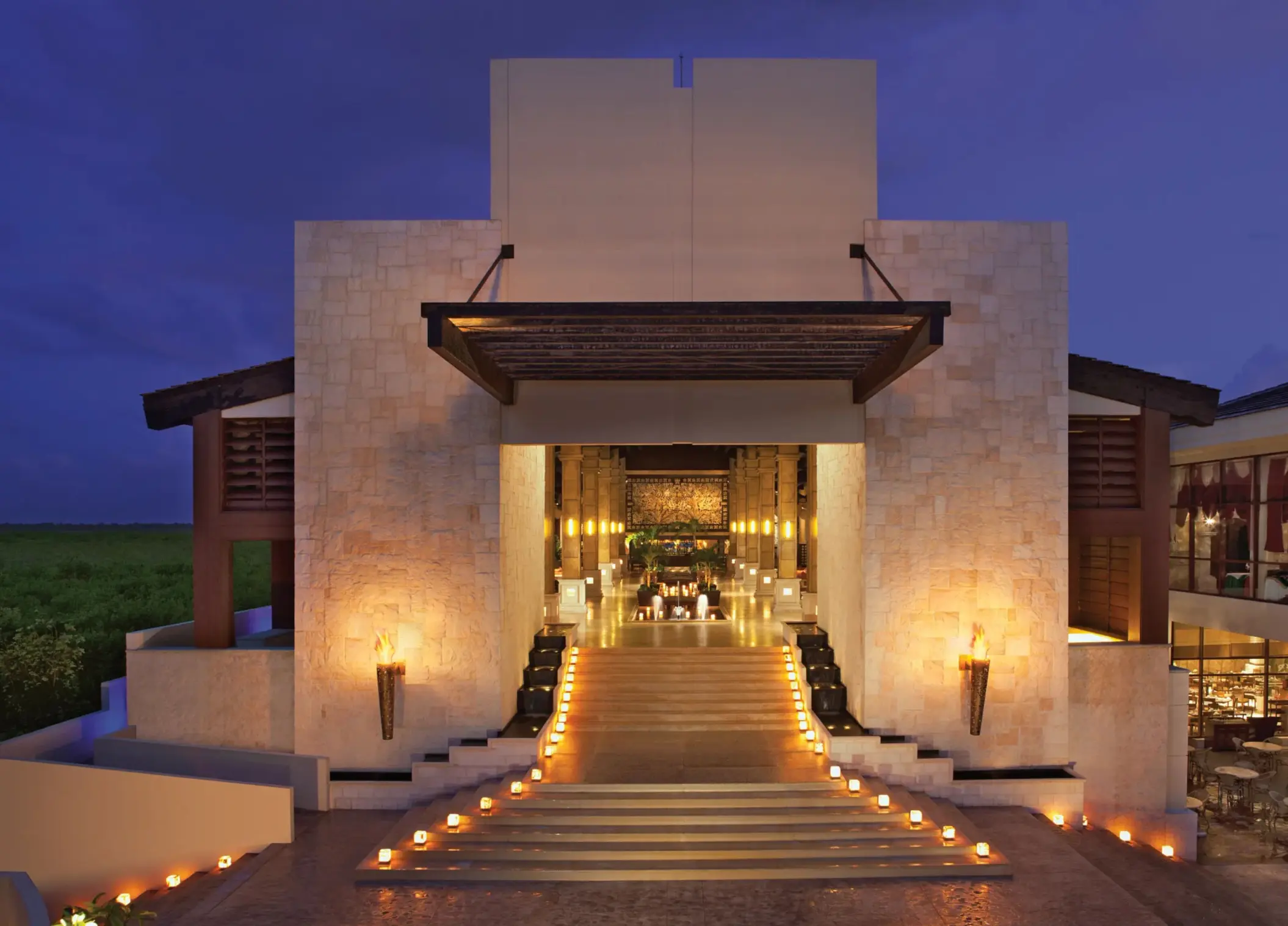 Resort lobby illuminated at night with candlelit steps and warm golden tones.