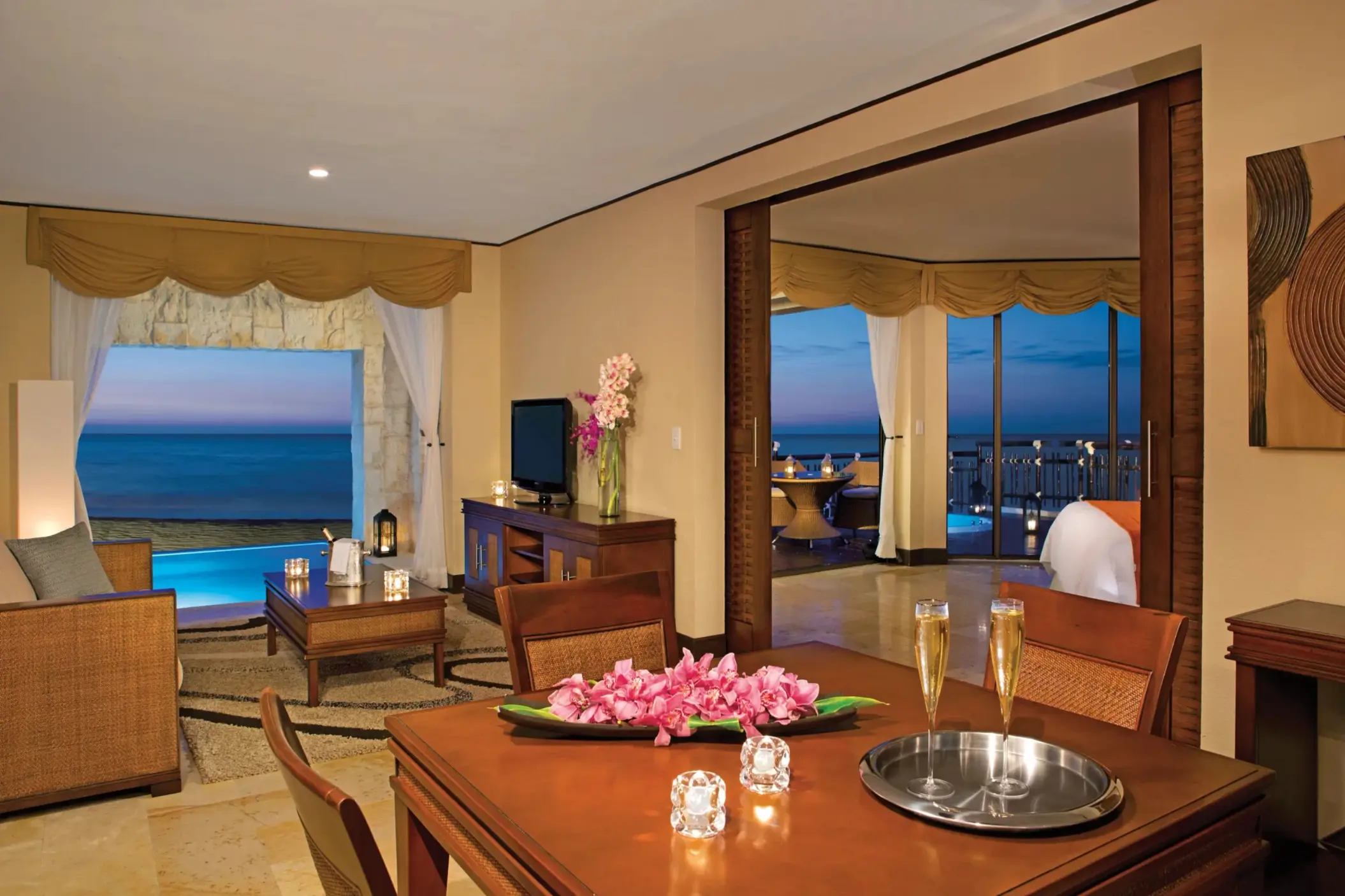Living and dining room with sunset ocean view and flowers.