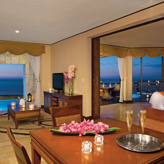 Living and dining room with sunset ocean view and flowers.