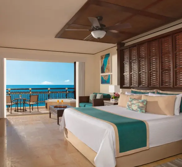 Ocean-facing Honeymoon Suite with king bed, seating area, and bright balcony view.