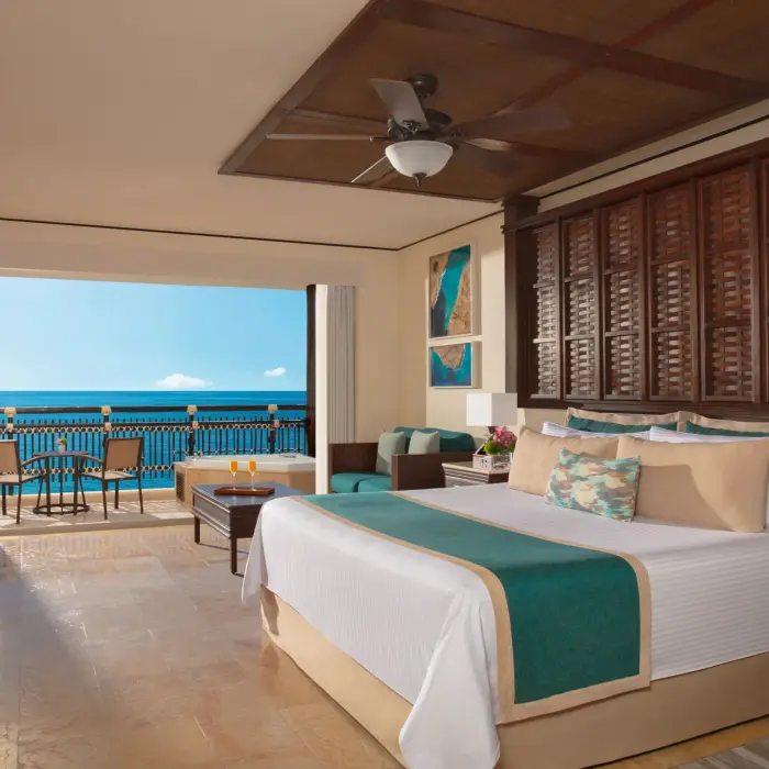 Ocean-facing Honeymoon Suite with king bed, seating area, and bright balcony view.