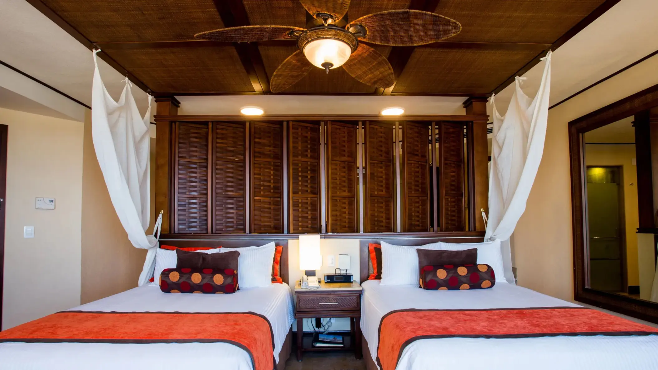 Accessible premium deluxe room with double beds, ceiling fan, and cozy tropical decor.