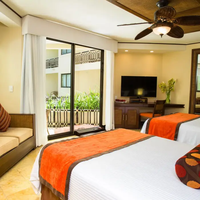 View from accessible deluxe room featuring double beds, modern seating area, and private balcony.