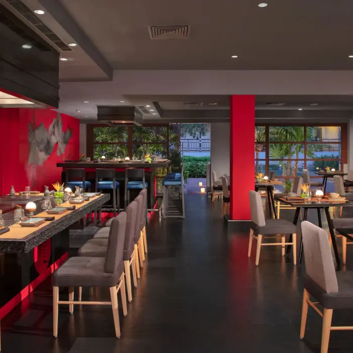 Asian fusion restaurant Himitsu at Dreams Riviera Cancun showcasing teppanyaki tables and bold red walls.
