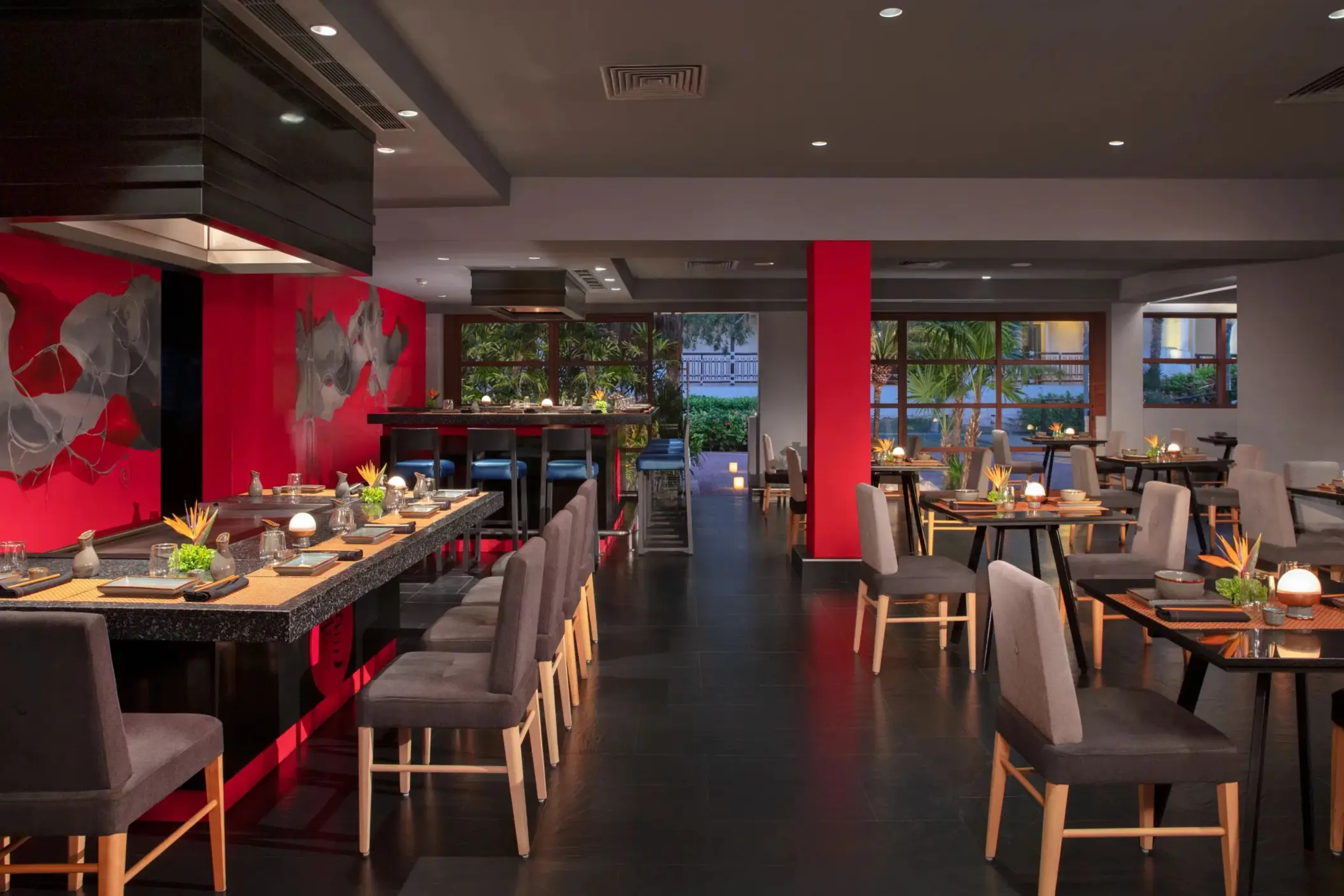 Asian fusion restaurant Himitsu at Dreams Riviera Cancun showcasing teppanyaki tables and bold red walls.