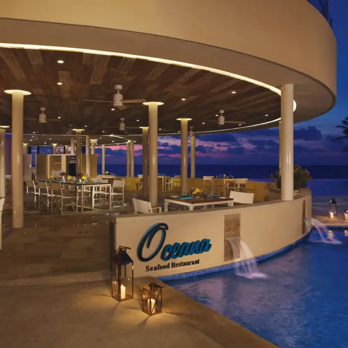 Oceana Seafood Restaurant at Dreams Riviera Cancun, a poolside oceanfront venue with sunset lighting.