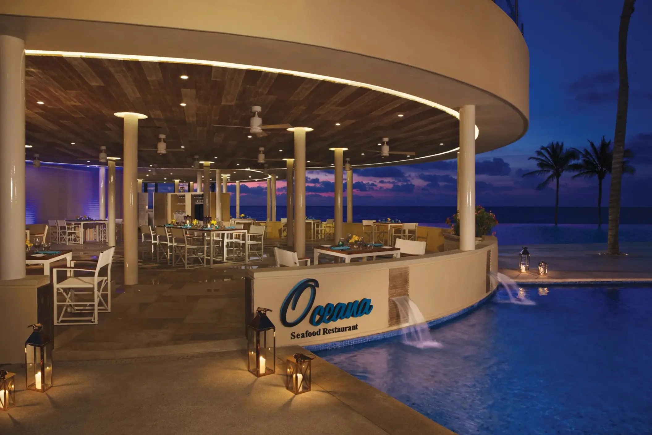 Oceana Seafood Restaurant at Dreams Riviera Cancun, a poolside oceanfront venue with sunset lighting.