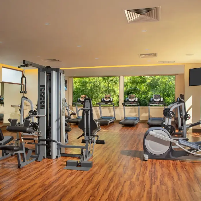 Fully equipped fitness center with cardio machines, strength equipment, and jungle views at Dreams Riviera Cancun.