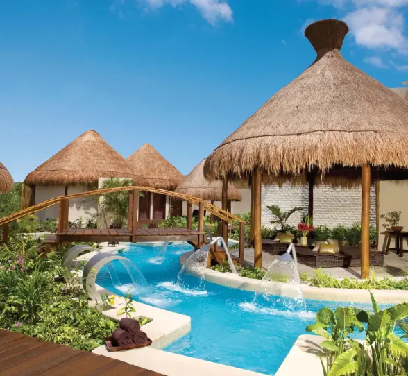 Tropical hydrotherapy spa garden with thatched palapas, aqua jets, and lush vegetation at Dreams Riviera Cancun.