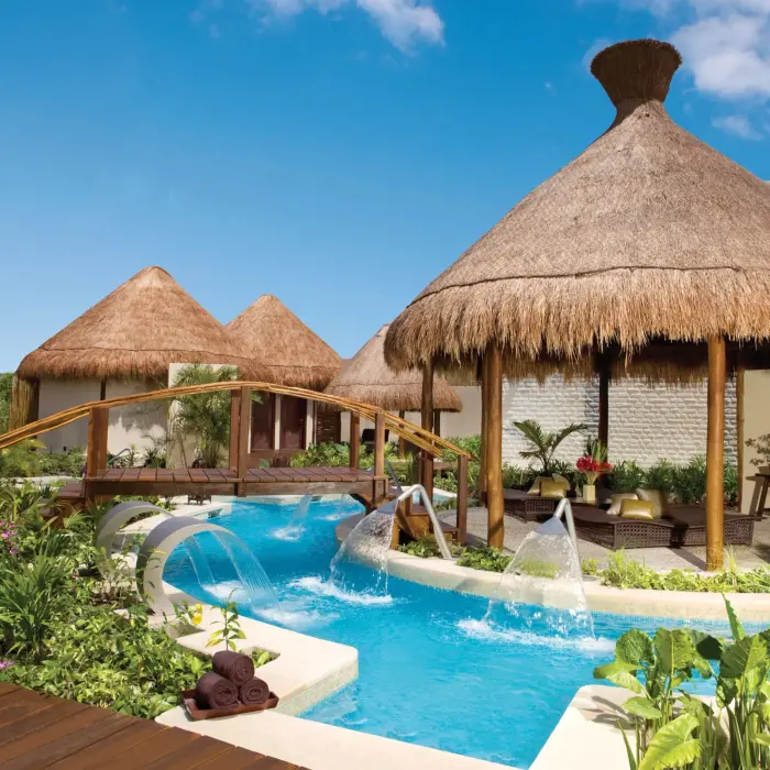 Tropical hydrotherapy spa garden with thatched palapas, aqua jets, and lush vegetation at Dreams Riviera Cancun.