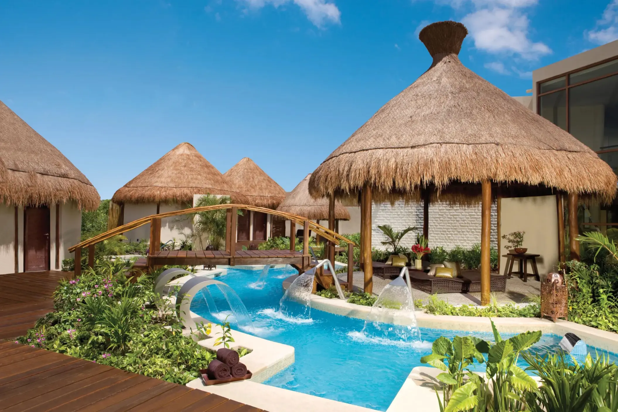 Tropical hydrotherapy spa garden with thatched palapas, aqua jets, and lush vegetation at Dreams Riviera Cancun.