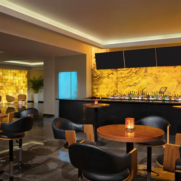 Indoor cocktail bar with amber-colored backlit wall and elegant black seating.