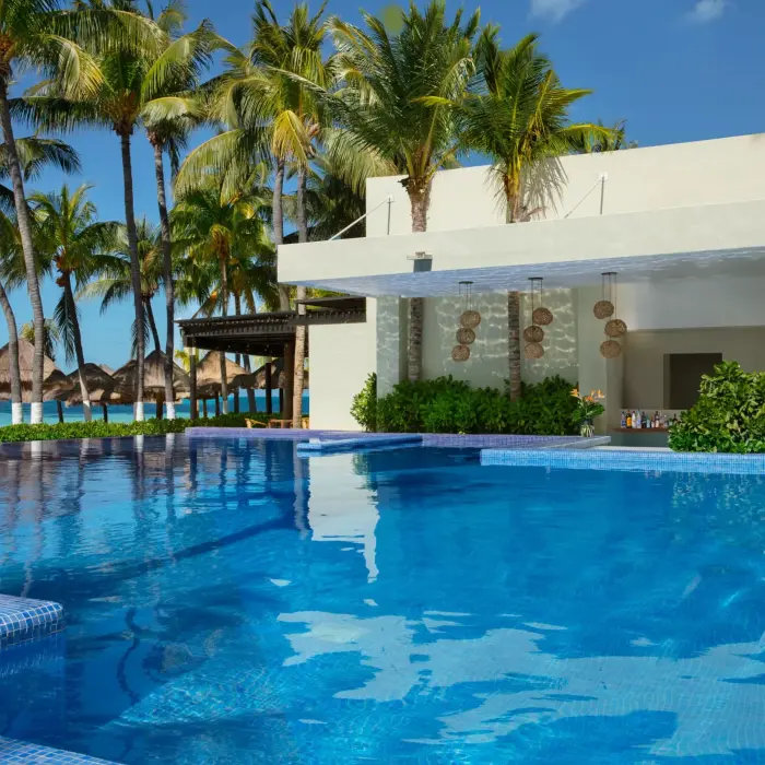 Swim-up bar in infinity pool surrounded by tropical greenery and ocean breeze.