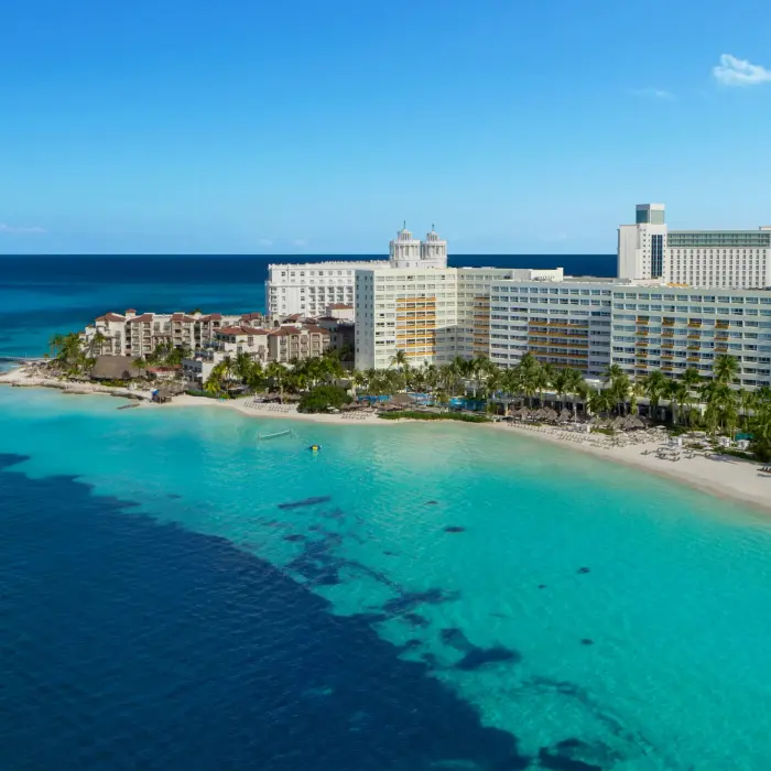 Aerial view of beachfront resort with turquoise water and sandy shores in Cancun.
