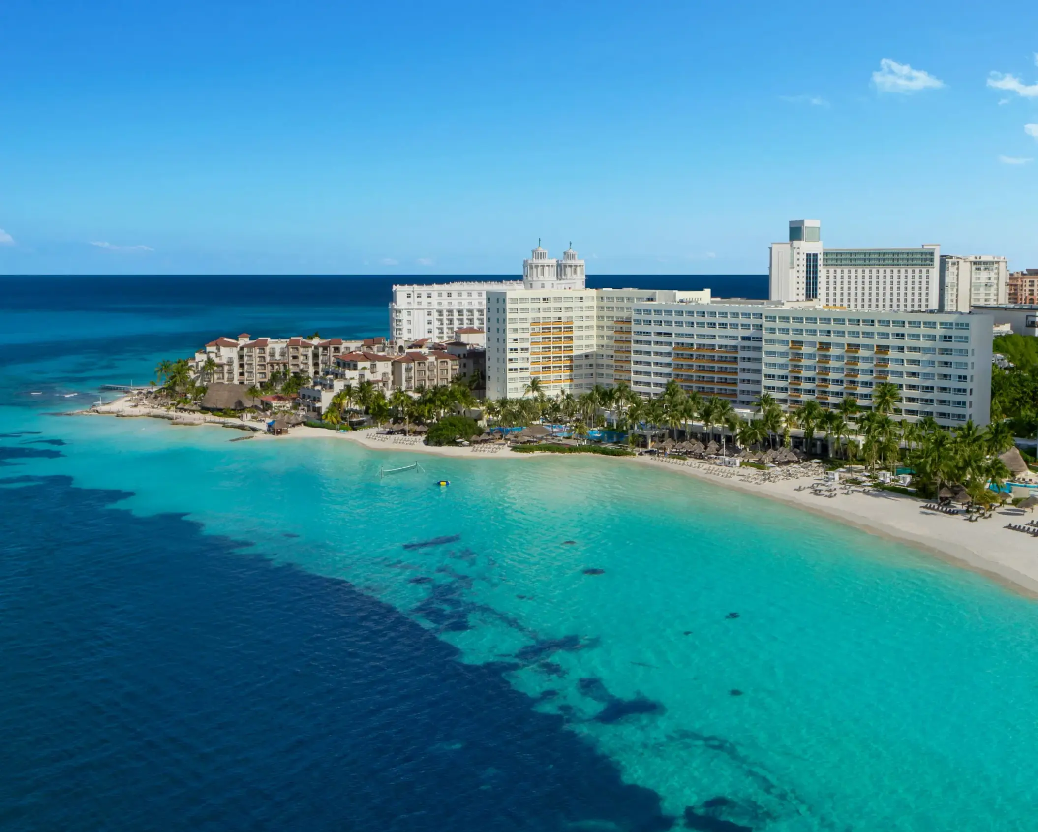 Aerial view of beachfront resort with turquoise water and sandy shores in Cancun.