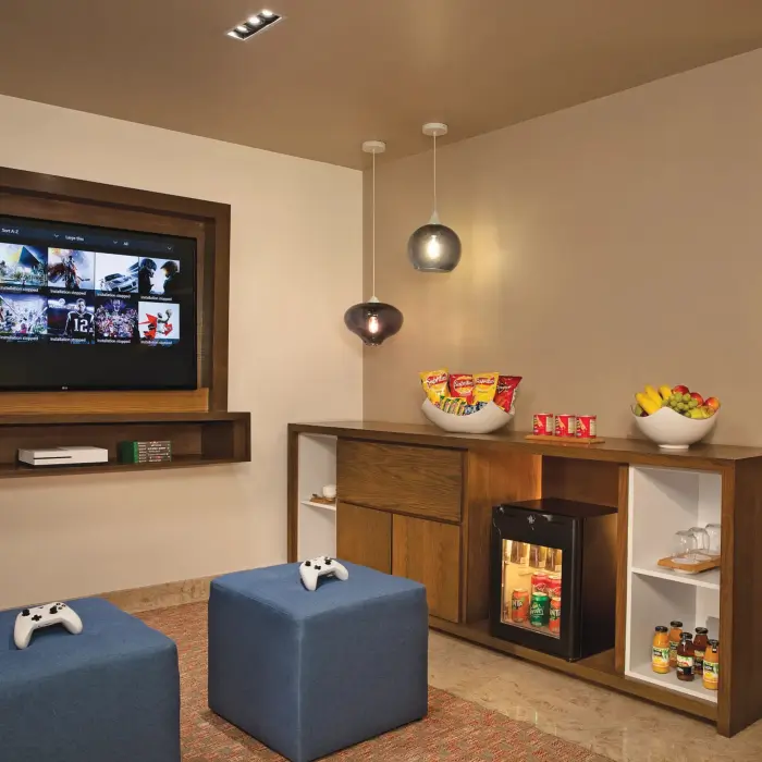 Game room with wall-mounted TV, Xbox console, snacks, and drinks for family entertainment.