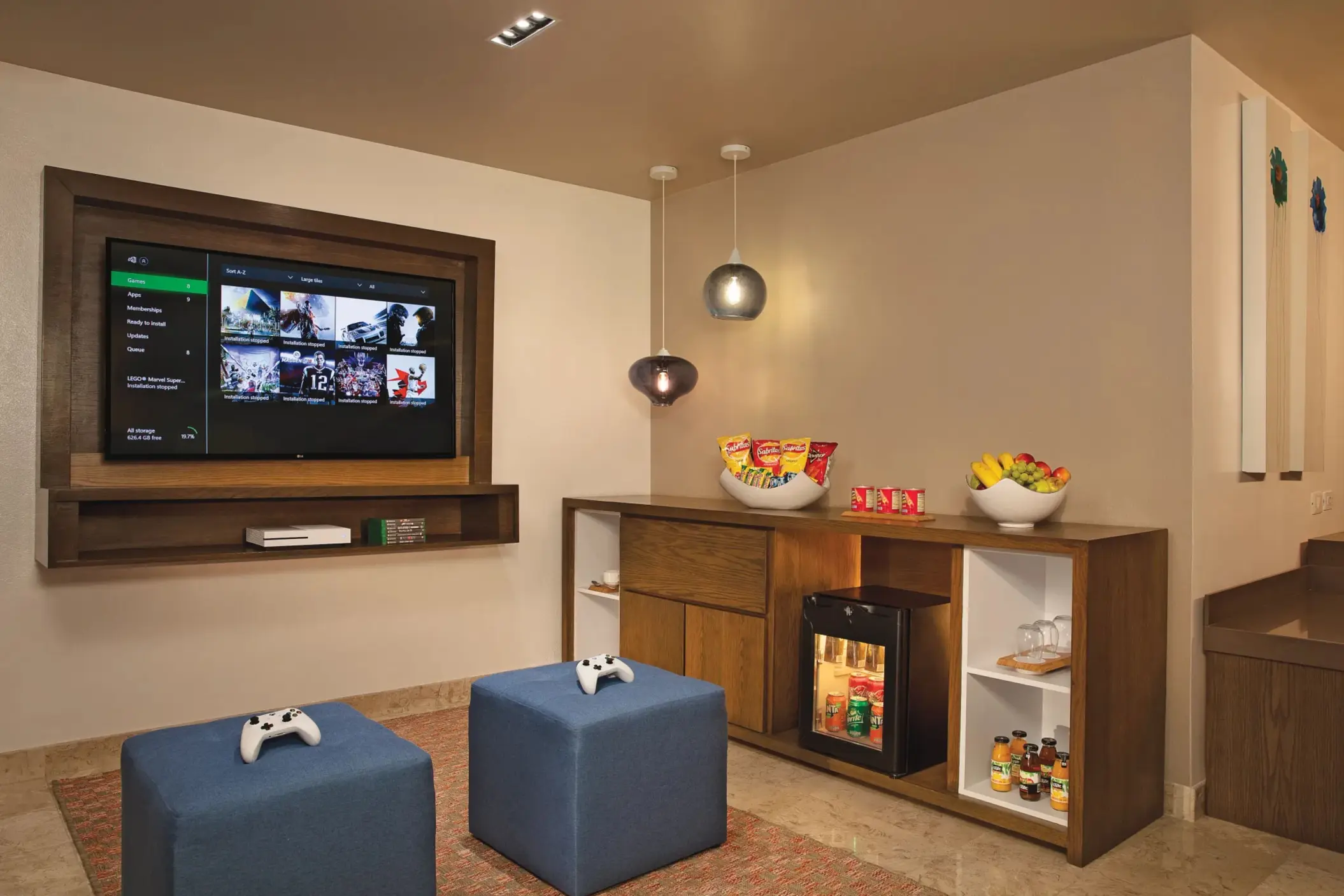 Game room with wall-mounted TV, Xbox console, snacks, and drinks for family entertainment.