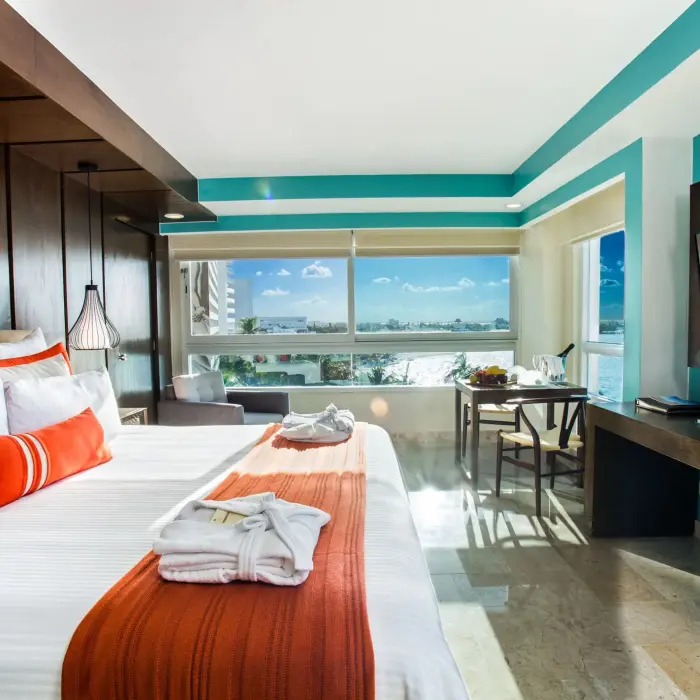 Corner room with bright accents, large windows, and a king bed facing ocean and city views.