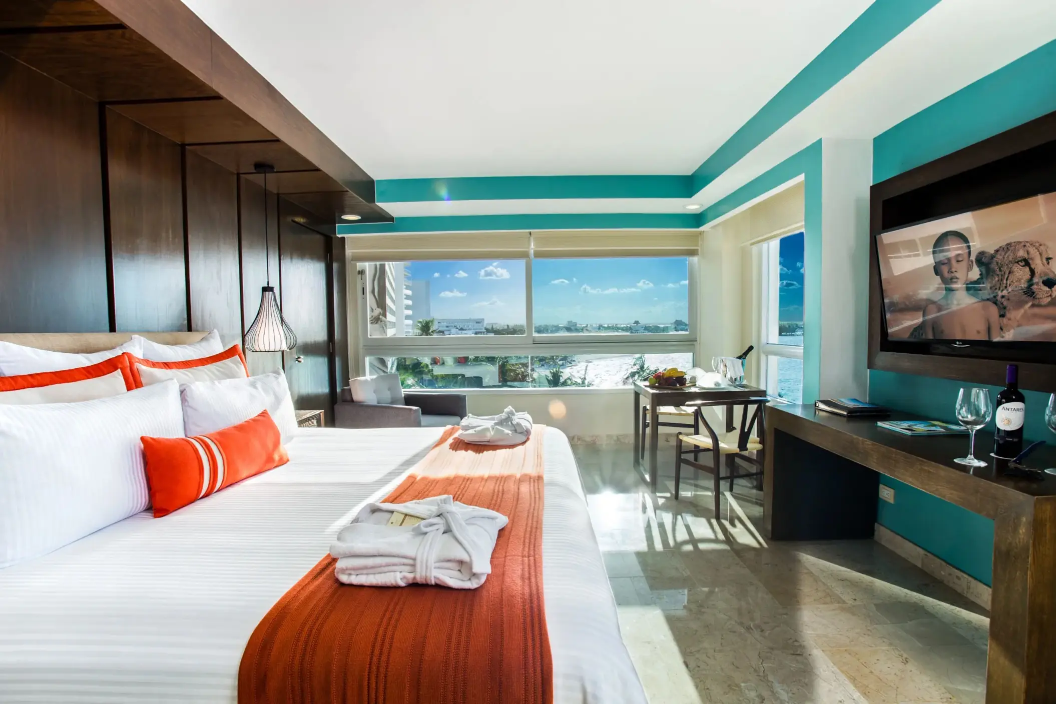Corner room with bright accents, large windows, and a king bed facing ocean and city views.