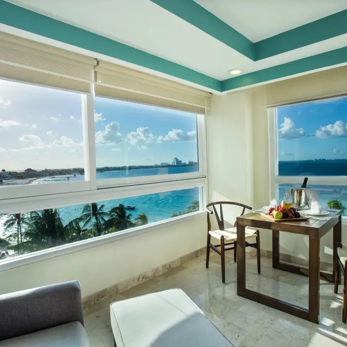 Stunning coastal view from a corner window with dining setup and turquoise ocean in the distance.