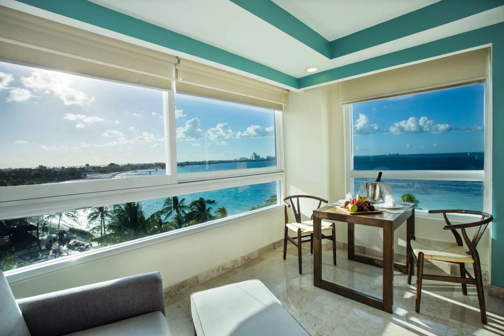 Stunning coastal view from a corner window with dining setup and turquoise ocean in the distance.