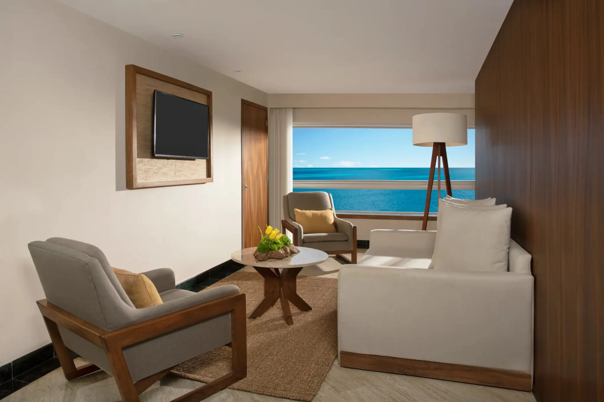 Junior Suite living space with sofa, desk, and TV, overlooking a tropical terrace with private plunge pool.